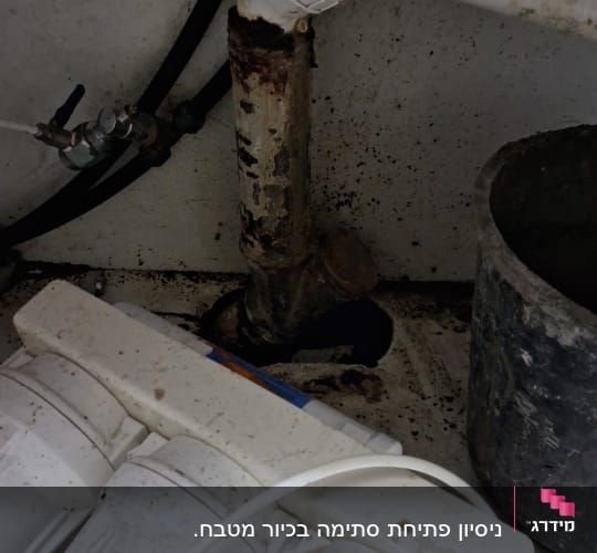 צינור מים עם חלודה וחיבורים מתחת לכיור